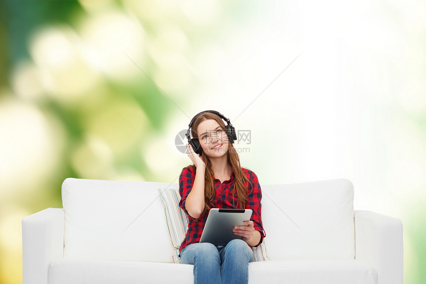用耳机和平板电脑坐在沙发上的女孩音乐立体声生态闲暇打碟机幸福音乐播放器长椅药片微笑图片
