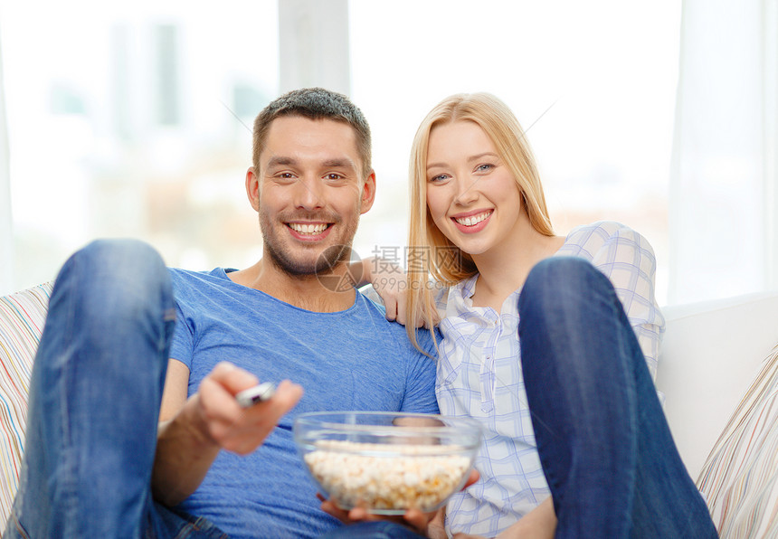 带着爆米花微笑的一对夫妇在家看电影电影男人男生女性成人女孩恋人按钮女士小吃图片