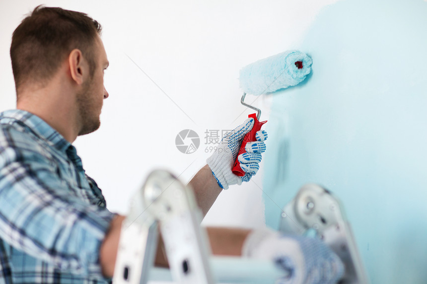 身戴手套的男性穿着手套 手持绘画滚筒装修房子装潢男人改造蓝色材料工具维修画家图片