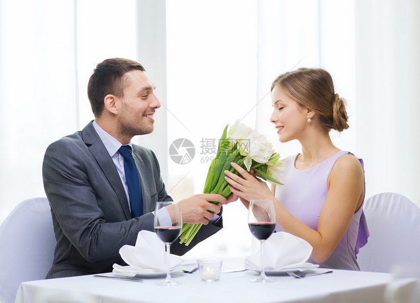 男人笑着在餐厅送花束眼镜展示女朋友生日花朵丈夫庆典夫妻家庭妻子图片