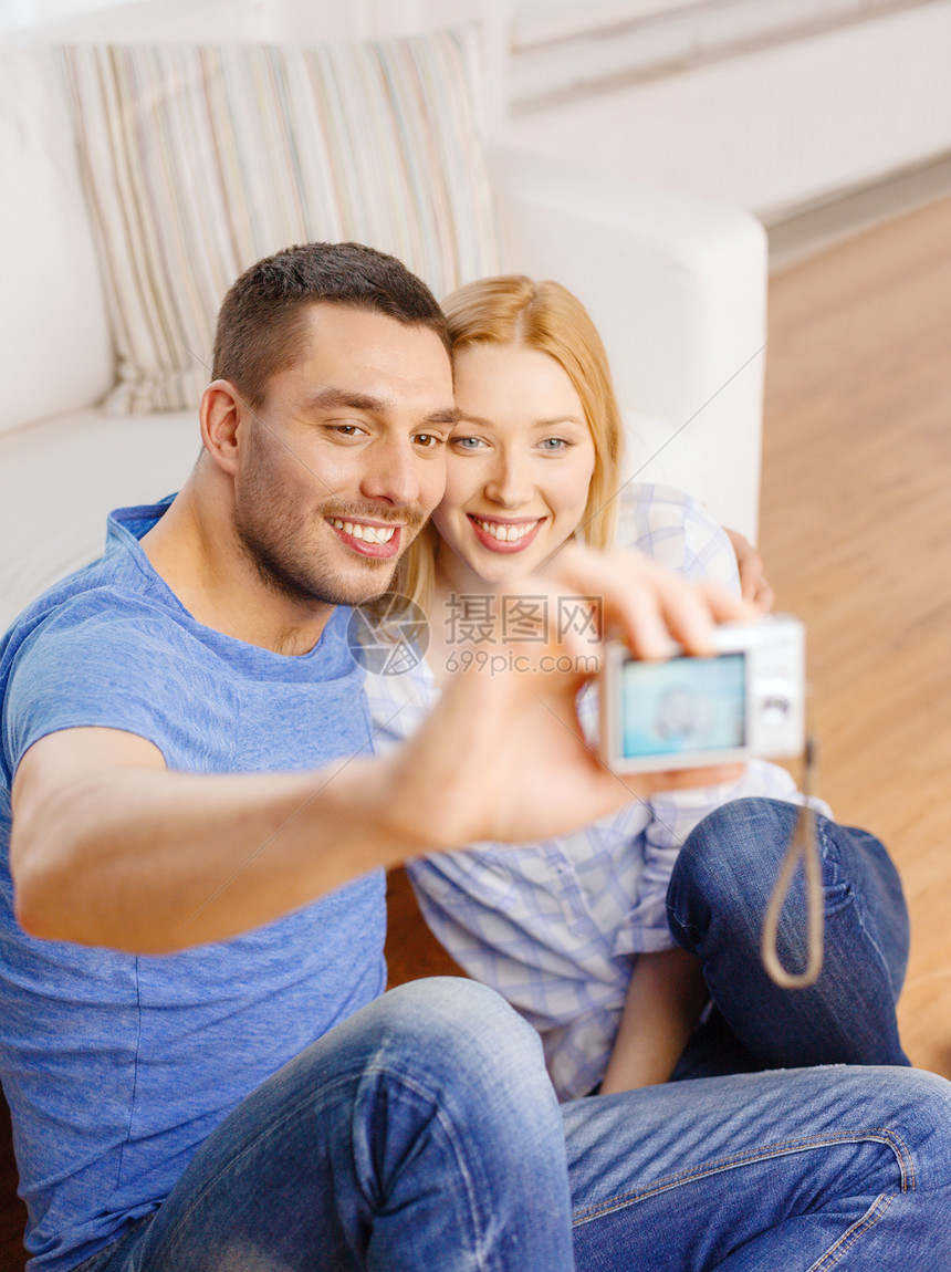 带数码相机拍摄照片的情侣微笑沙发家庭技术图画快乐地面长椅恋人地毯女士图片