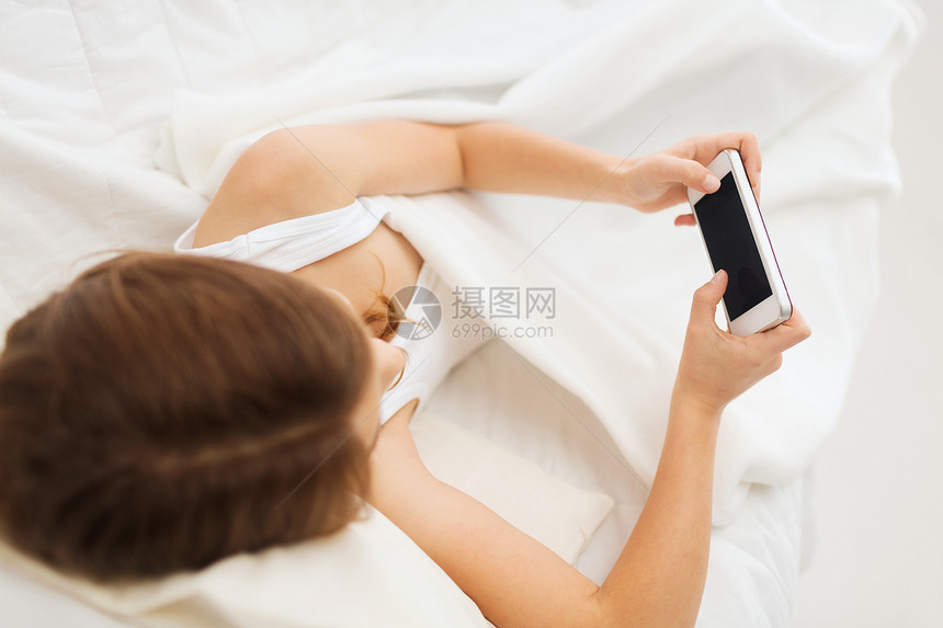 小女孩在家中与智能手机一起躺在床上休息时间说谎幸福娱乐细胞游戏女孩就寝互联网图片
