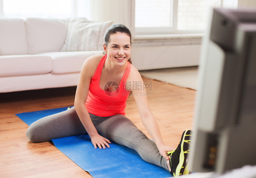 微笑着的少女在家中地板上尖叫健身房运动女性身体有氧运动地面女孩电视重量损失图片