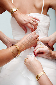 女人亲手帮新娘扣上优雅的婚纱高清图片