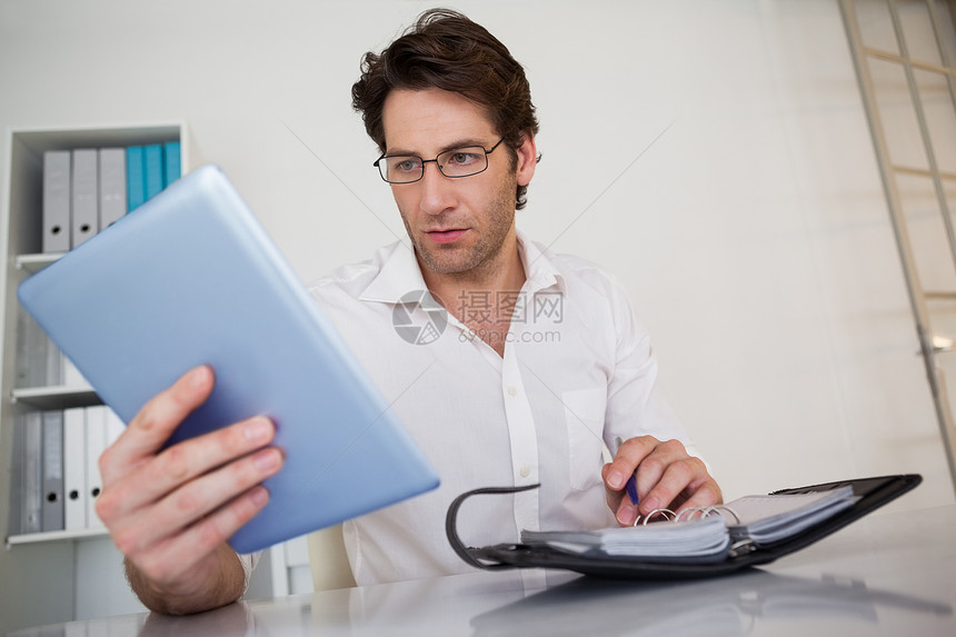 临时商务人士在办公桌安排他的日程安排日记平板桌子办公室规划师商业组织专注触摸屏电脑图片