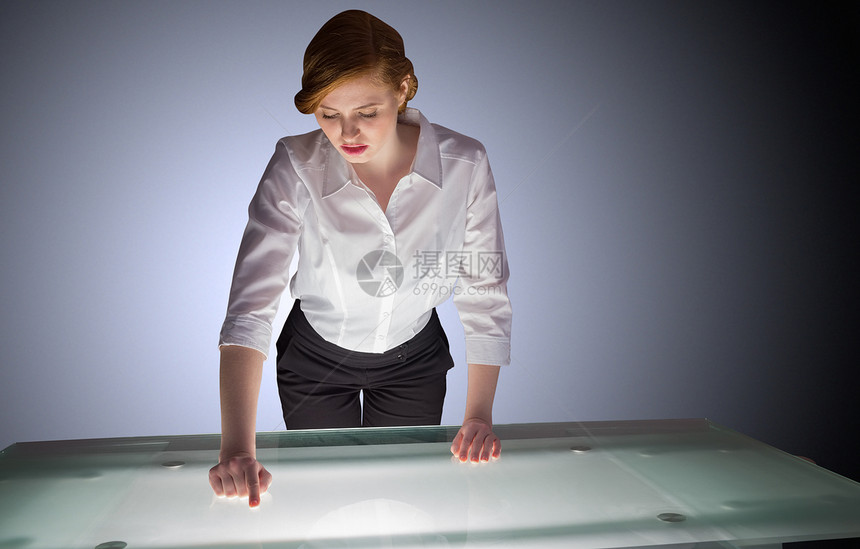 红头女商务人士站在桌上指着桌子站着图片