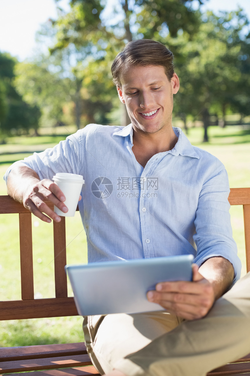 坐在公园长椅上使用平板饮料咖啡的微笑者绿地杯子咖啡杯电脑快乐男性热饮农村触摸屏药片图片