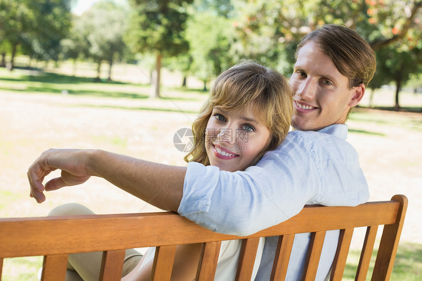 一对夫妇在公园长椅上放松 一起笑着看镜头感情微笑男人男性男朋友女士阳光衬衫太阳绿地图片