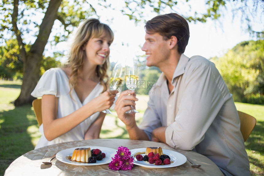 可爱的一对快乐的情侣坐在外面 举杯敬酒与香槟和D图片