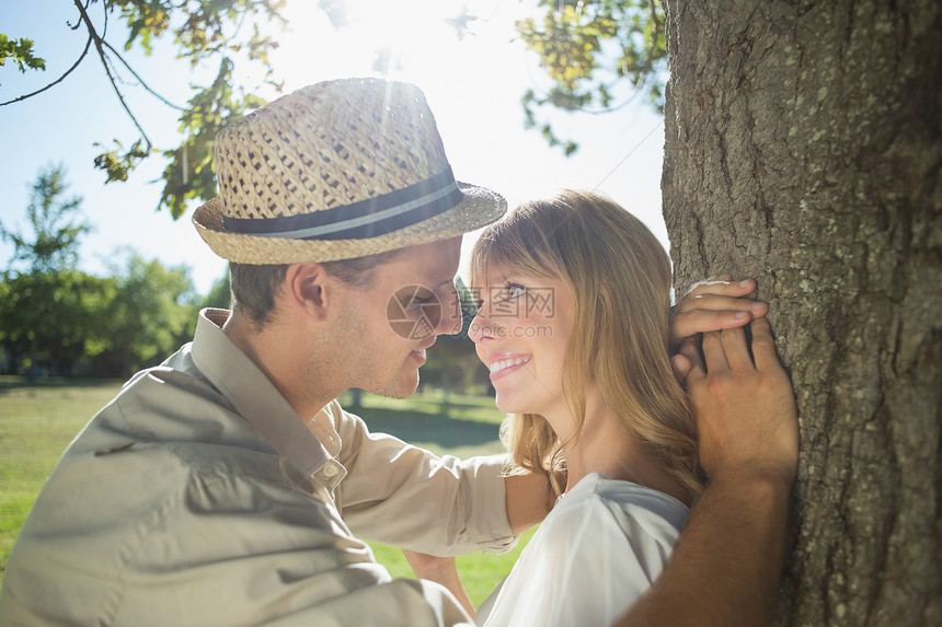 可爱笑着的情侣靠在公园树上女士阳光男人快乐男性金发女郎裙子夫妻感情农村图片