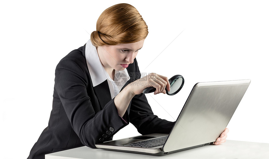 使用笔记本电脑的红头女商务人士放大镜桌子女士人士女性公司红发技术职业好奇心图片