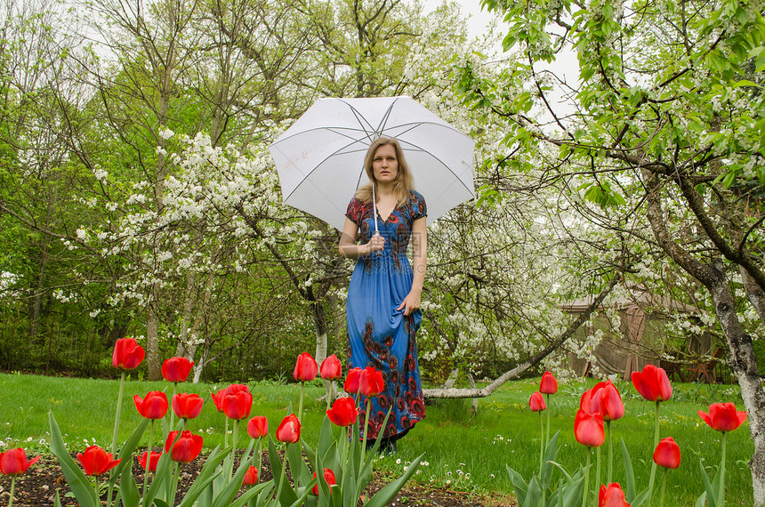 穿着服装的少女用雨伞装上公园花朵图片