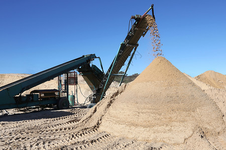 挖掘出来的沙铺和筛选机天空机器腰带传送带谷物矿业蓝色沙丘白色植物背景