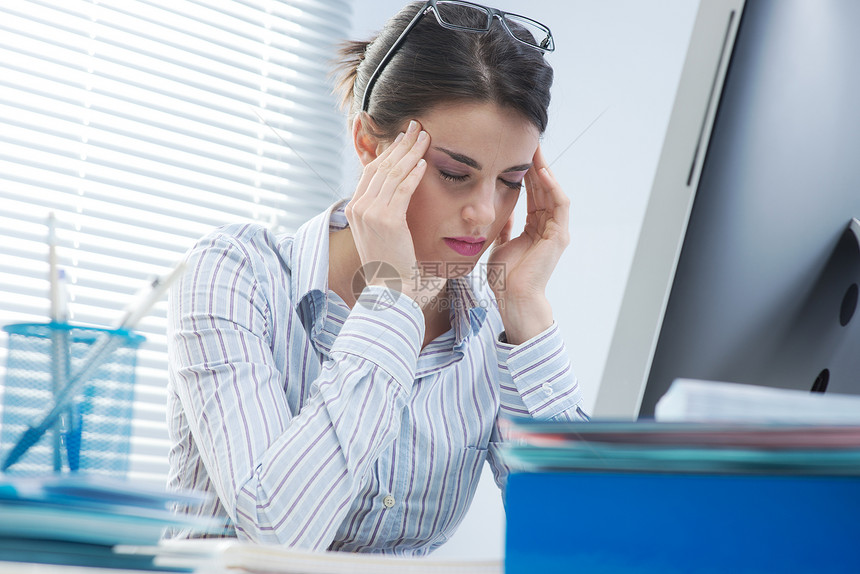 患有头痛的疲劳女商务人士工作文书计算机压力百叶窗桌子疼痛寺庙设备情绪图片