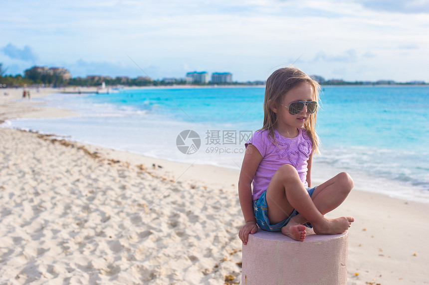 坐在异国海滩的莲花沙滩上的可爱的小姑娘童年赤脚婴儿女儿女性裙子海洋热带假期姿势图片