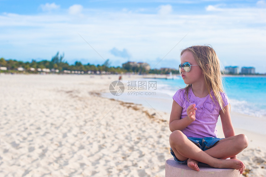 坐在异国海滩的莲花沙滩上的可爱的小姑娘蓝色幸福裙子女孩热带姿势赤脚孩子海岸平衡图片