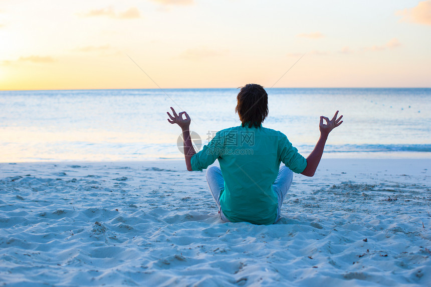 坐在白沙滩的莲花位置上的年轻男子天堂热带精神情调冥想快乐身体海岸异国蓝色图片