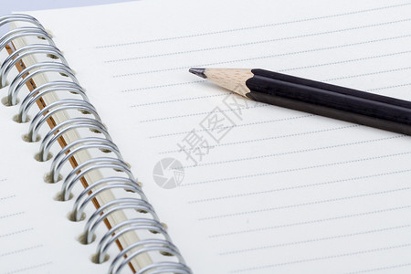 笔记本上的铅笔特写拍摄写作木头笔记办公室教育软垫戒指商业文档白色背景图片