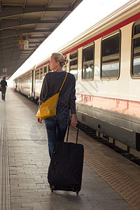 包平台素材女士在火车站等着呢旅行城市手提箱女性平台假期时间过境行李民众背景