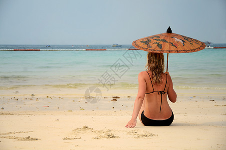 女人睡在沙滩上海岸线海滩形状假期比基尼地点白色女性太阳成人背景图片