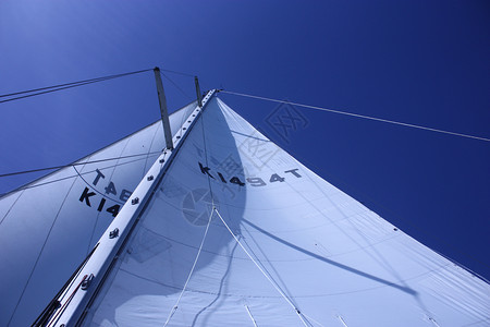 从下面的甲板上看到游艇帆和护航运动钻机航行天空波浪白色桅杆风帆索具帆船背景图片