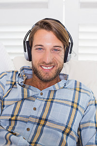躺在沙发上听音乐的冷酷微笑的男人背景图片