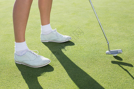 女士高尔夫球员在投绿色阳光推杆晴天球鞋爱好活动高尔夫球运动员闲暇假期背景图片