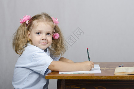 坐在桌子上写笔记本的小女孩爱好教程女孩训练铅笔喜悦乐趣瞳孔背景图片