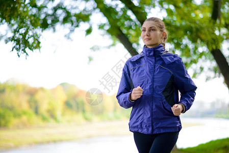 运动夹克年轻美丽的女子在秋天公园奔跑赛跑者运动锻炼成人训练夹克卫生女性耐力慢跑者背景