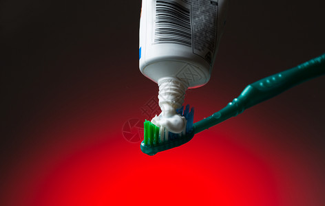 红上牙刷和牙膏塑料红色牙科卫生化妆品整洁宏观绿色白色管子背景图片