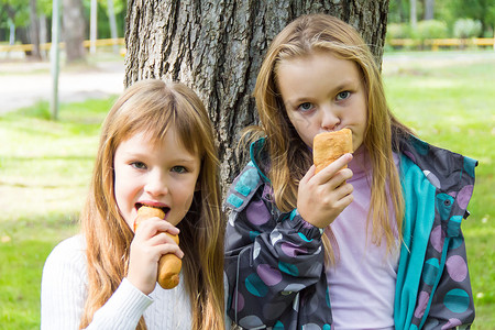 两个吃女孩的可爱童年白色女学生女性孩子金发背景图片