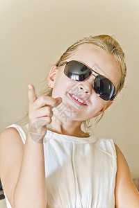 玩墨镜的可爱女孩蓝色孩子童年金发白色微笑女学生太阳镜背景图片