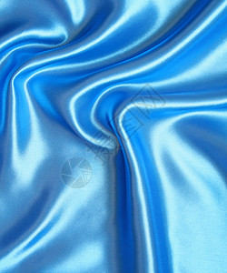 平滑优雅的蓝色丝绸作为背景天蓝色海浪织物银色纺织品材料投标布料折痕曲线背景图片