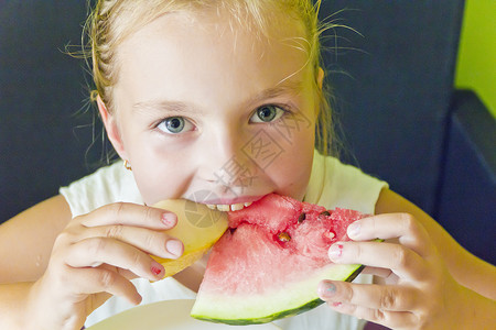 可爱的女孩吃西瓜和甜瓜白色金发童年女学生蓝色孩子背景图片
