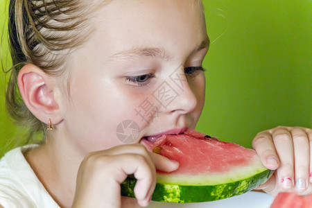 可爱的女孩吃西瓜童年白色女学生金发孩子蓝色背景图片