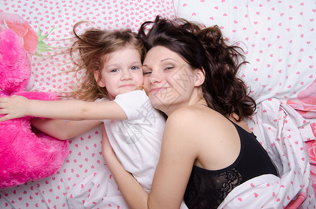 女儿找一个柔软的玩具 跟妈妈躺在一起背景图片