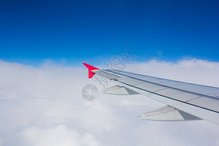 机翼飞机在云上飞翔 从西向天空仰望红色旅行喷射蓝色技术窗户引擎运输航班翅膀背景