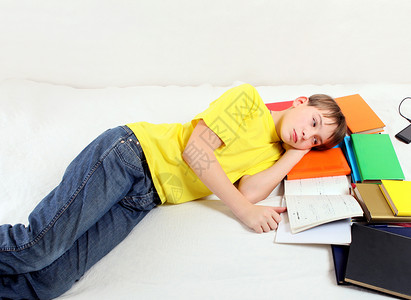 疲倦的青少年 有一本书沙发男生图书瞳孔失败小伙子青年手册考试轨枕背景图片