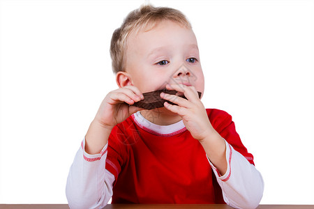 小男孩吃着一整块巧克力棕色孩子们快乐甜点喜悦糖果金发微笑孩子食物背景图片
