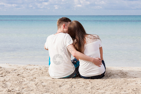 男人沙滩夏天坐在沙滩上的浪漫的年轻情侣女性幸福海岸男性女孩友谊喜悦蓝色海滩旅行背景