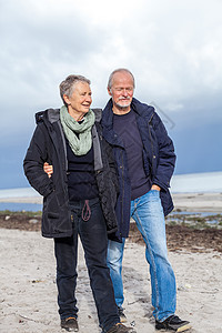 快乐的老年老人夫妇在海滩上散步退休夫妻友谊丈夫女士娱乐男人妻子海岸背景图片
