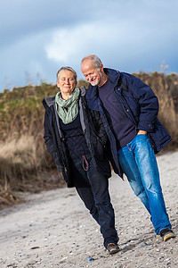 快乐的老年老人夫妇在海滩上散步友谊退休女士夫妻男人丈夫妻子娱乐海岸背景图片
