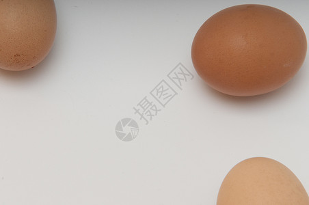 三个鸡蛋蛋黄白色灯光椭圆形黄色背景图片
