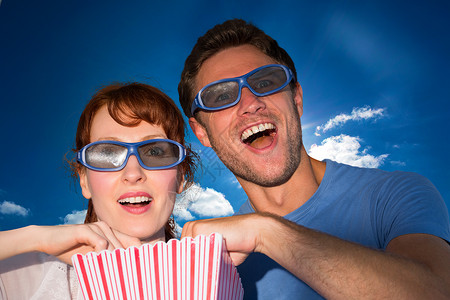 情侣享受电影之夜的复合形象夫妻男性幸福眼镜计算机夜游爆米花阳光短发天空背景图片