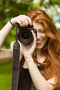 闲暇单反相机公园中美丽的女摄影师闲暇微笑绿地技术长发女性草地单反相机摄影背景