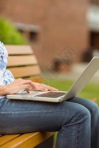 使用膝上型电脑坐在长椅上的妇女背景图片
