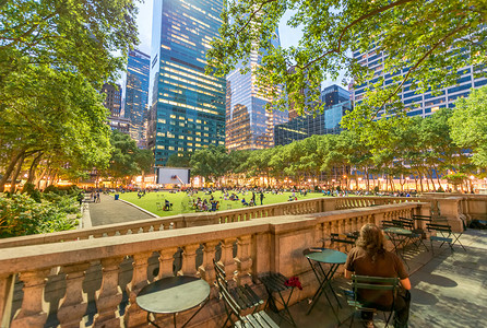 纽约市布赖恩特公园室外餐厅区城市民众草地蓝色建筑物摩天大楼桌子椅子建筑绿色背景图片