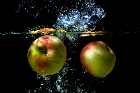 苹果掉入水中绿色红色飞溅运动水果背景液体食物水滴黑色背景图片