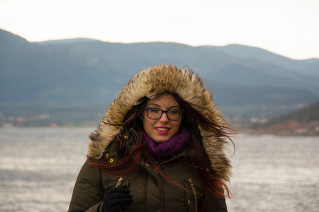 参加冬季游览的年轻女孩紫色旅行眼镜夹克山脉兜帽围巾背景图片