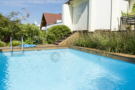 现代大楼旁边游泳池的游泳池运动别墅财产房子花园阳光锻炼奢华水池房地产背景图片